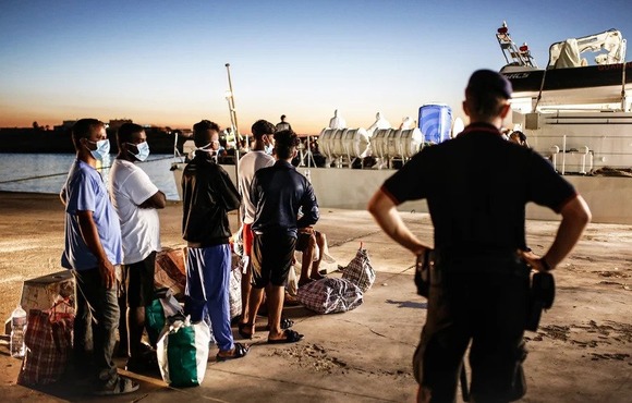 Asylum seekers and migrants wait on the Italian island of Lampedusa to board a coast guard ship bound for Sicily.
