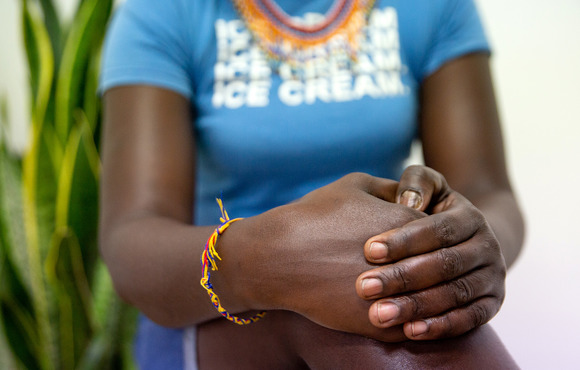 the hands of a woman sitting down are clasped on her knee.