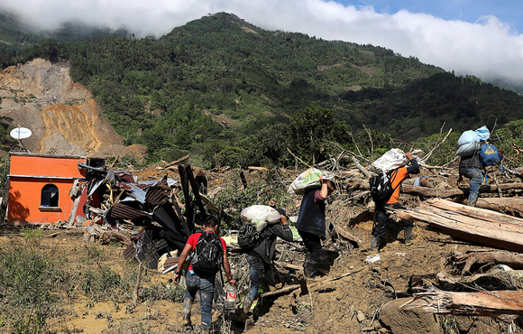 Residents carry belongings recovered from their houses, as the search for victims continues after a mudslide buried the village of Queja in Guatemala's Alta Verapaz department, on 8 November 2020.