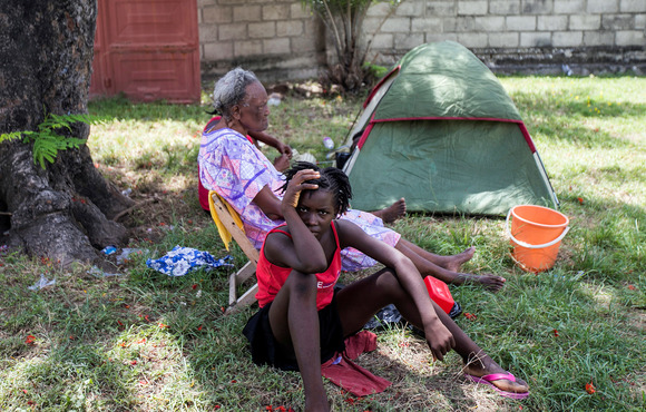 Two women sit in the shade at a makeshift encampment set up on a soccer field after Saturday's 7.2-magnitude quake, in Les Cayes, Haiti on 16 August 2021. 