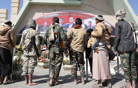 Armed members of the Houthi movement stand facing away from the camera outside the grave of senior official Saleh al-Sammad at al-Sabeen Square in Sana'a, Yemen, 11 January 2021