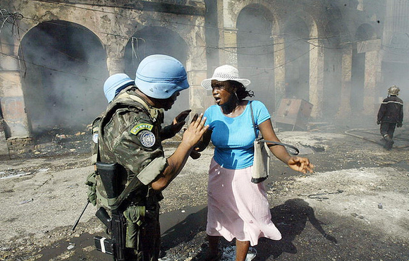 United Nations Stabilization Mission in Haiti (MINUSTAH) peacekeepers helping a street merchant in the downtown area of Port-au-Prince after a fire that ravaged 50 stores on 23 June 2004. Troops from the Brazilian contingent helped the Haitian National Po