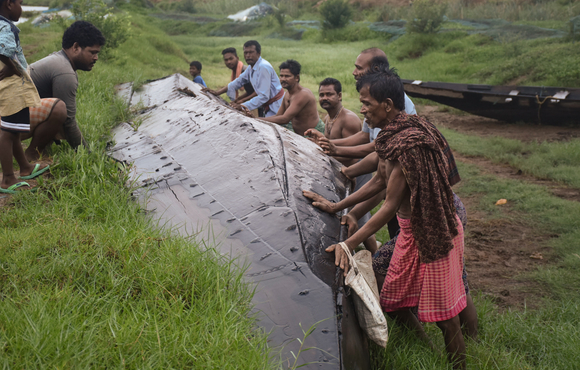 Photo of fishermen overturning a boat in a canal in India after Cyclone Fani.