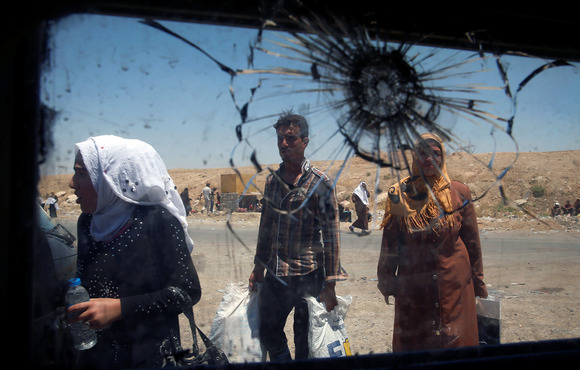 A few of several people through the back window of a car that is shattered with a bullet
