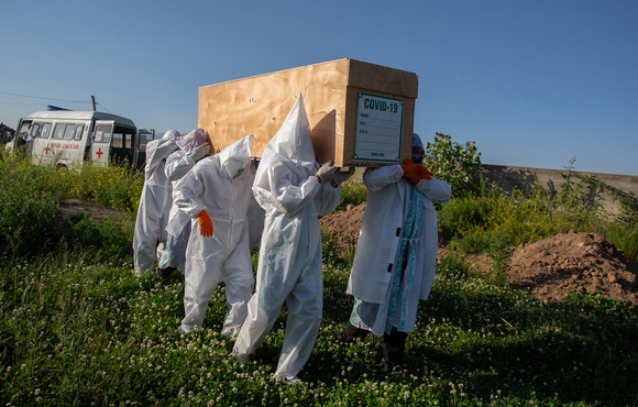 Volunteers and family members carry the wooden coffin of a woman who died from COVID-19