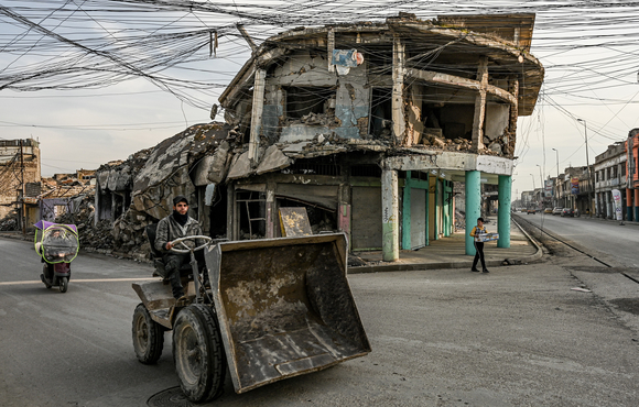 An image of a construction worker driving through a quiet intersection in west Mosul