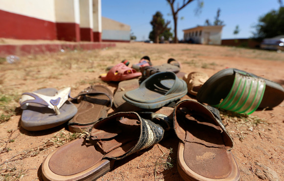 A close-up picture of a pile of shoes on a dirt road.