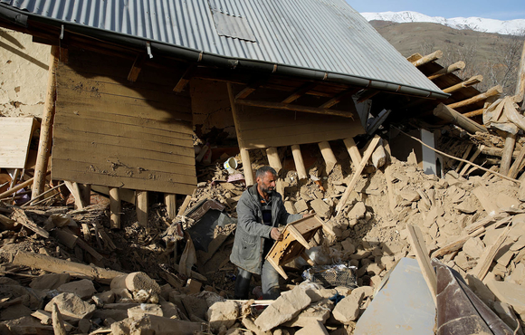 A man clears debris outside a house damaged in the earthquake in Cevrimtas.