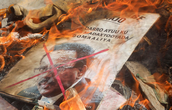 A poster lays on the ground on fire.