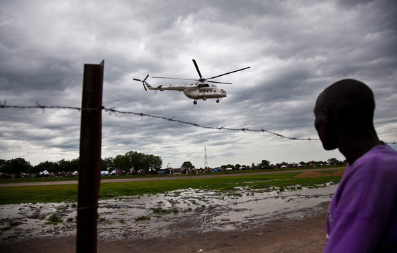 A man watches a UN helicopter land at an airstrip in South Sudan on 26 June 2012. The instrumentalisation of aid by political elites in the country is prompting a rethink of traditional humanitarian principles.
