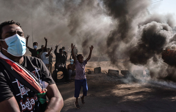 Protesters stand beside burning tyres during a demonstration in the Al-Sahafa neighbourhood of Khartoum on 25 November 2021. 