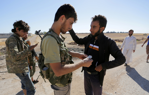 Rebel fighters inspect the identification papers of men in northern Syria