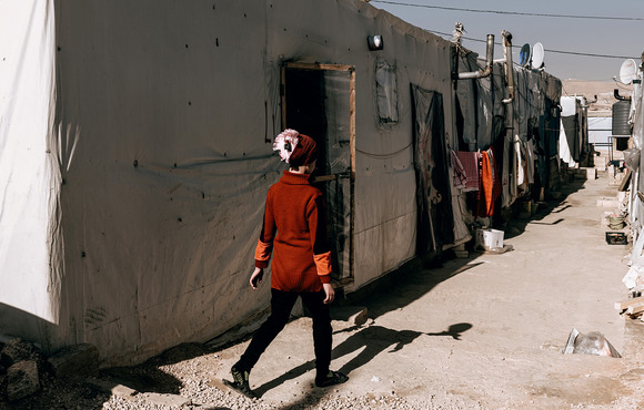 A Syrian refugee walks down an alley lined with makeshift tents at Rif Al Sham camp in the Bekaa Valley, Lebanon, in August 2020. 