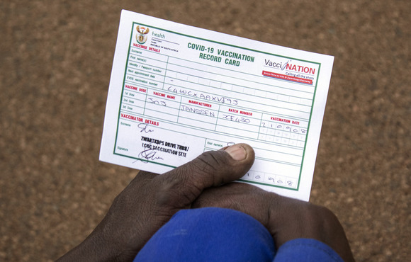 A person holds a vaccination certificate in their hand.
