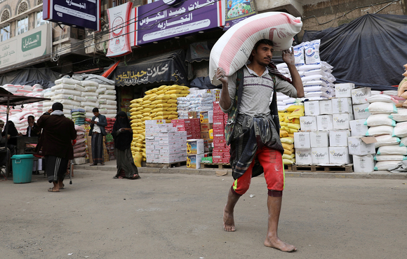 A worker carries a sack of wheat flour in Sana'a, Yemen