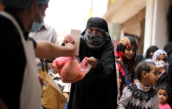 A worker hands out bread rations at a charity kitchen in Sana'a