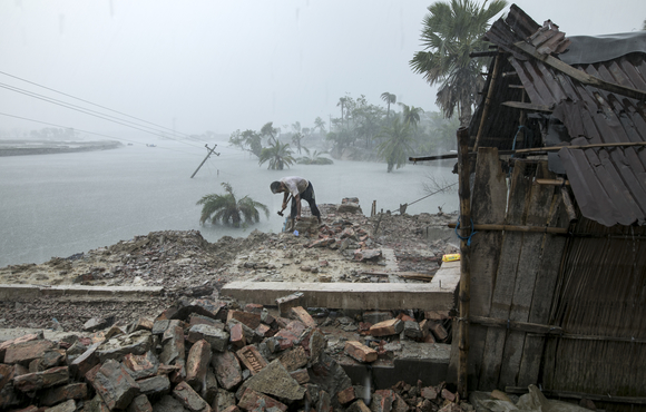 A man collects bricks from his house, which is submerged by daily tides months after May 2020's Cyclone Amphan, in Bangladesh’s Khulna district.